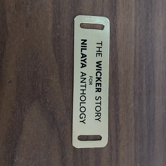 Single brass slot label The Wicker Story for Nilaya Anthology