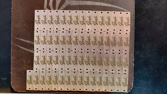 Sheet of small brass labels with a script logo