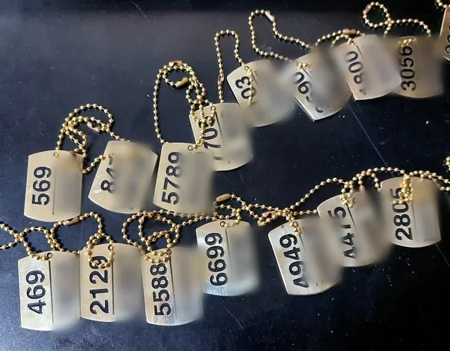 Brass dog tags with numbers and names, names hidden