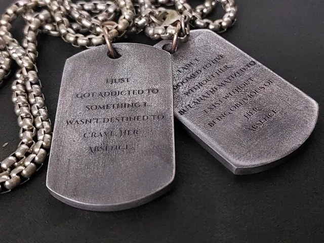 Two antique gunmetal dog tags engraved with a long quote
