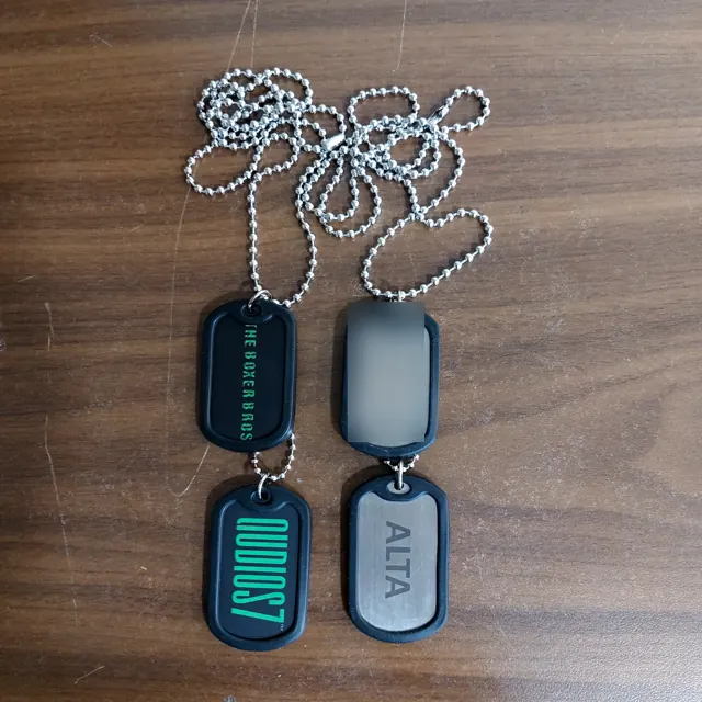 Dog tags in black rubber silencers with green colour-filled brand names; employee name hidden